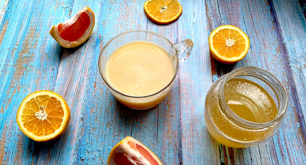 Iontový nápoj v športovom šejkry a rozkrojenými citrusmi a medom na modrom drevenom podklade