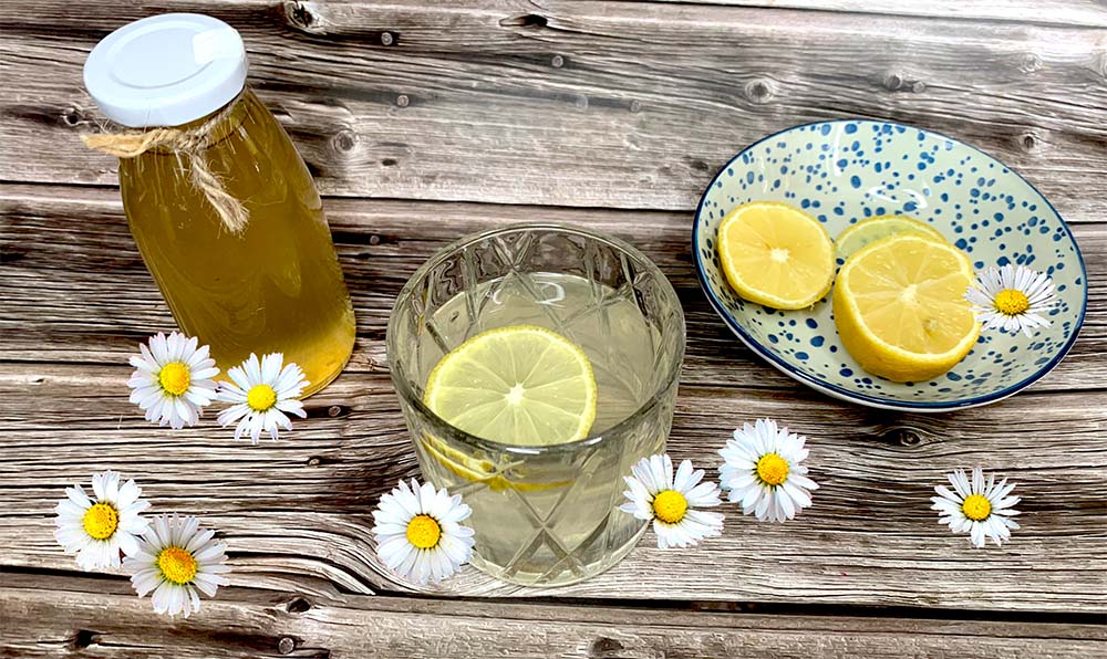 sedmokráskový sirup vo fľaške a v sklenenom pohári s citrónom