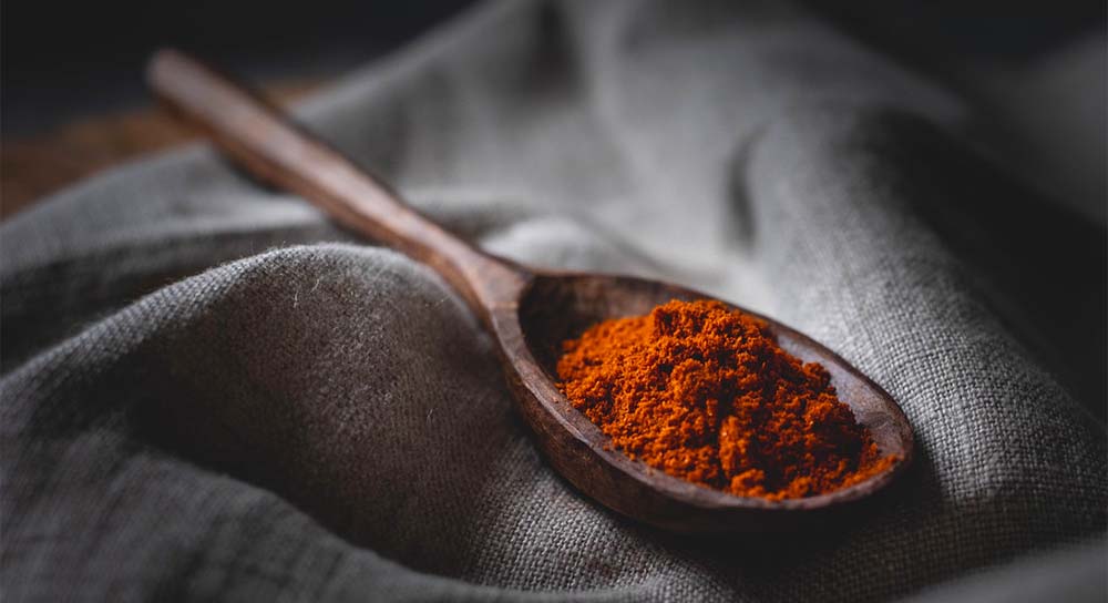 červená paprika v drevenej lyžičke položenej na prírodnej textílií